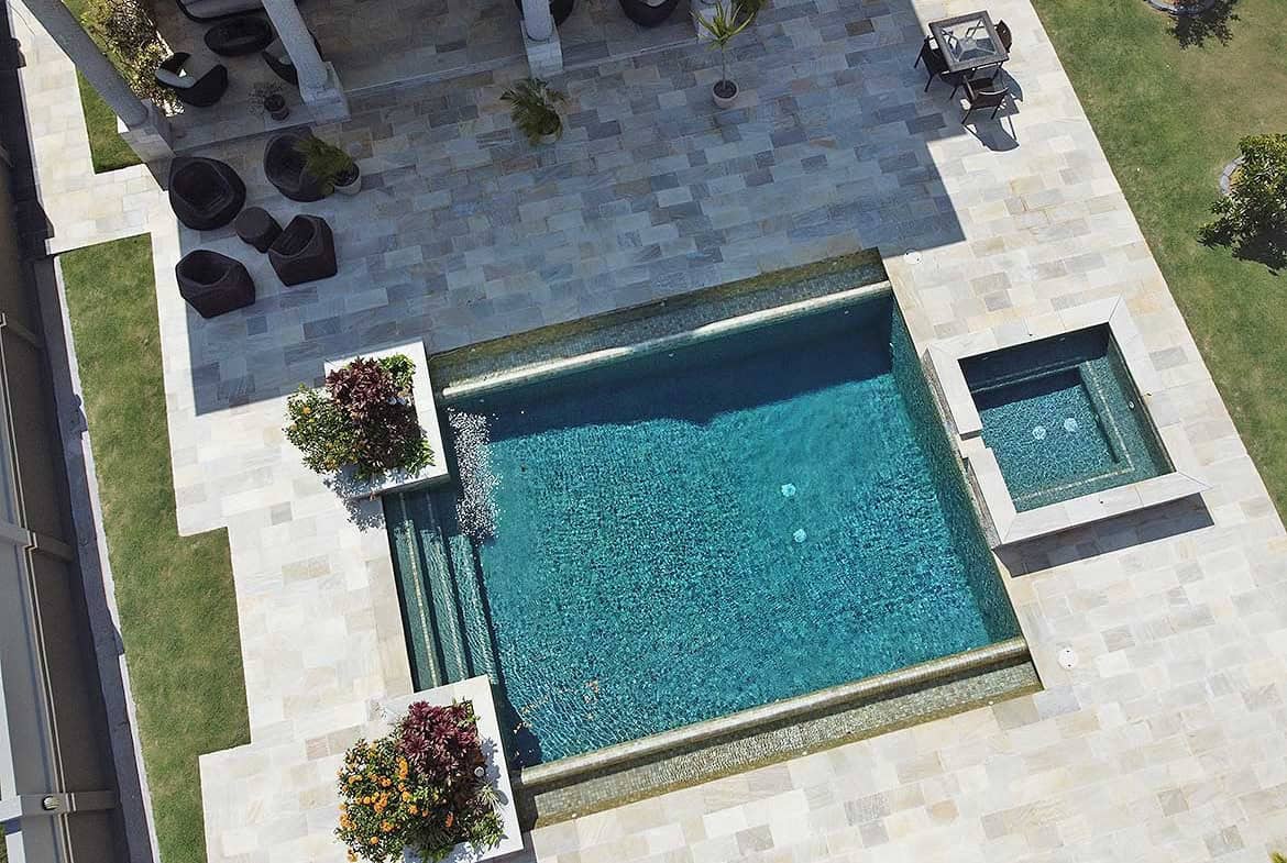 Cornerstone- Aerial view of a modern backyard pool with hot tub and outdoor seating.