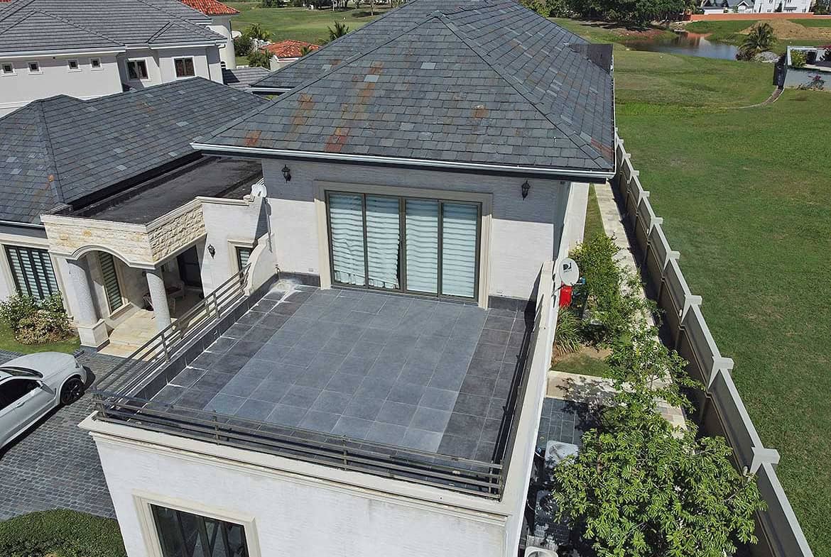 Cornerstone- A modern rooftop terrace with a glass railing and tiled flooring in a residential area.