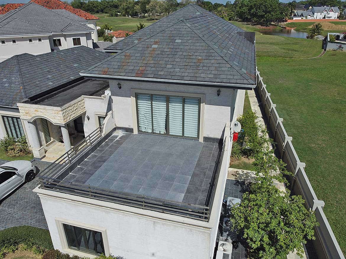 Modern residential rooftop terrace Cornerstone- A modern rooftop terrace with a glass railing and tiled flooring in a residential area.