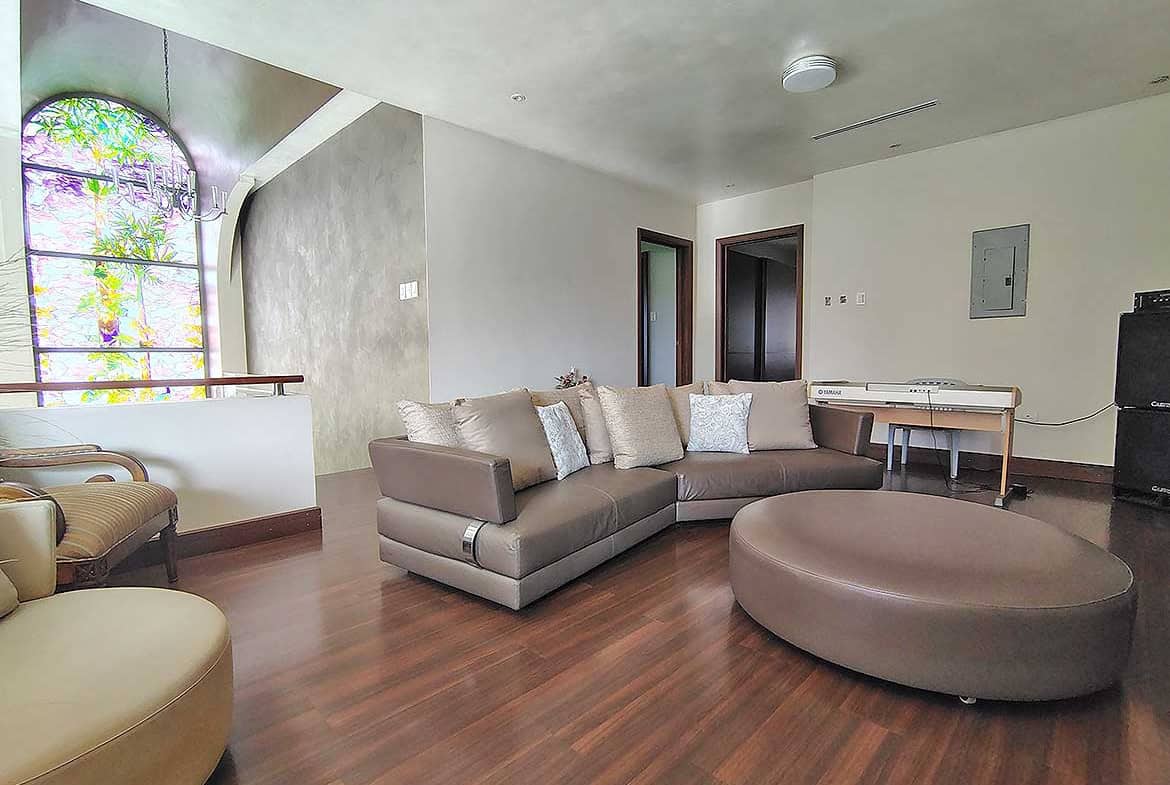 Cornerstone- Spacious living room with large sectional sofa and wooden flooring.