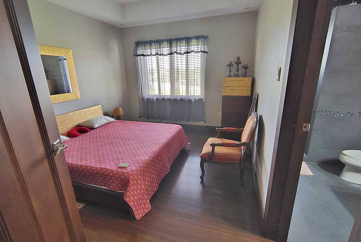 Cornerstone- Cozy bedroom with pink bedspread and vintage furniture.