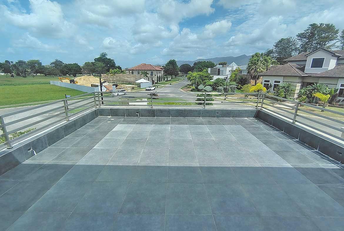 Cornerstone- Modern balcony with glass railing overlooking neighborhood and green fields.