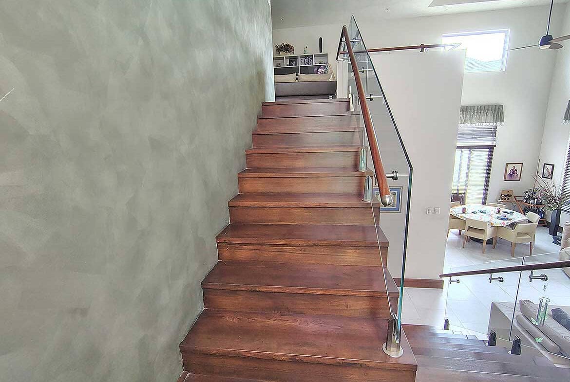 Cornerstone- Elegant wooden staircase with glass railing in contemporary home interior.