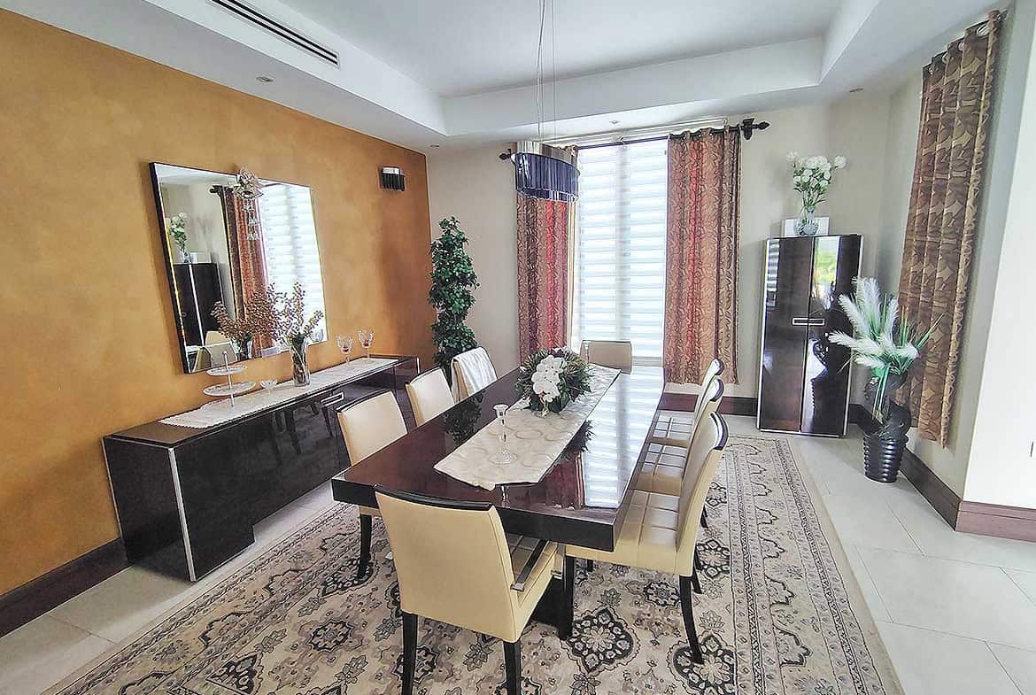Cornerstone- Spacious dining room with a large table, beige chairs, and decorative curtains.