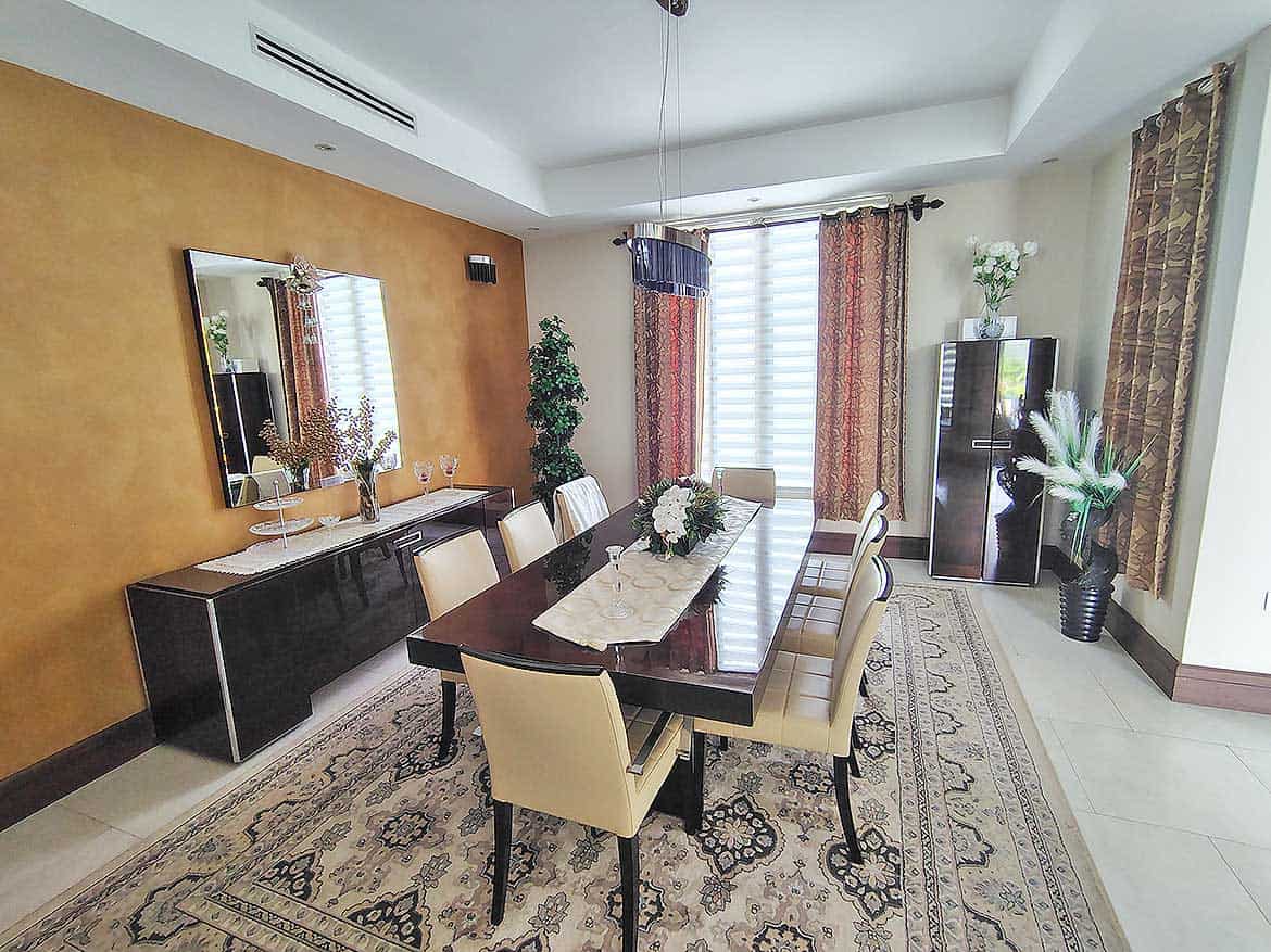 Elegant Dining Room with Modern Decor Cornerstone- Spacious dining room with a large table, beige chairs, and decorative curtains.