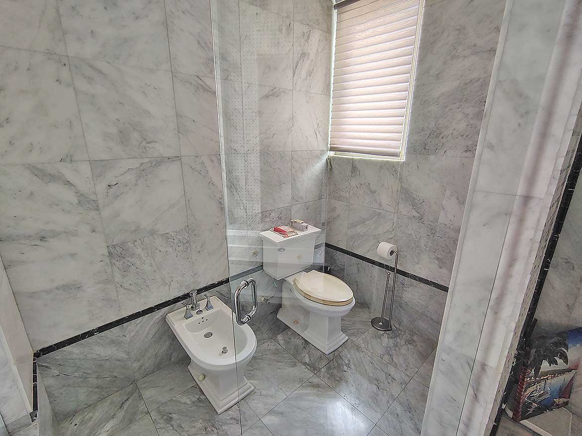 Modern Bathroom at Millennium Lakes Home Cornerstone- Contemporary bathroom with marble walls, toilet, bidet, and window with blinds.