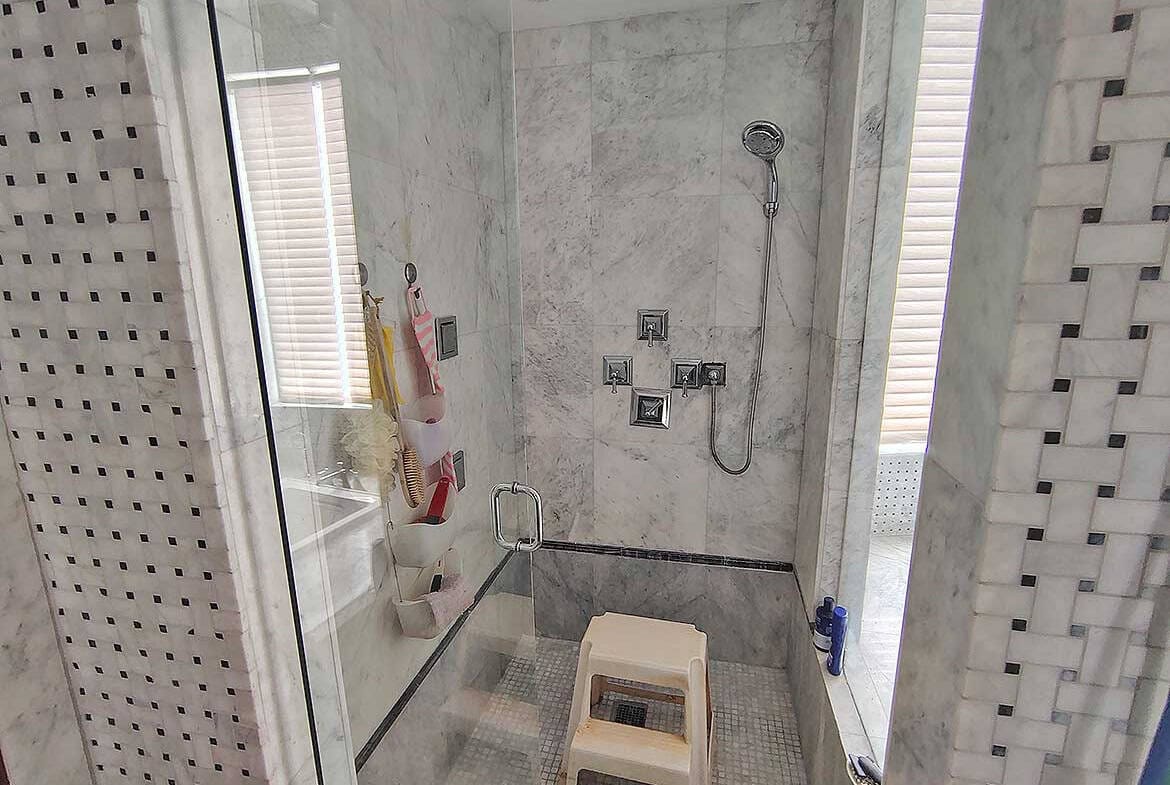 Cornerstone- Contemporary walk-in shower with marble tiles and glass enclosure at Millennium Lakes Home.