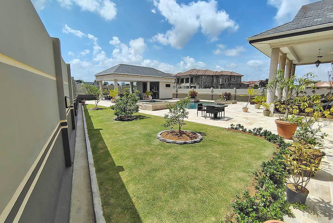 Cornerstone- Beautiful landscaped backyard with lawn, trees, and outdoor seating area.