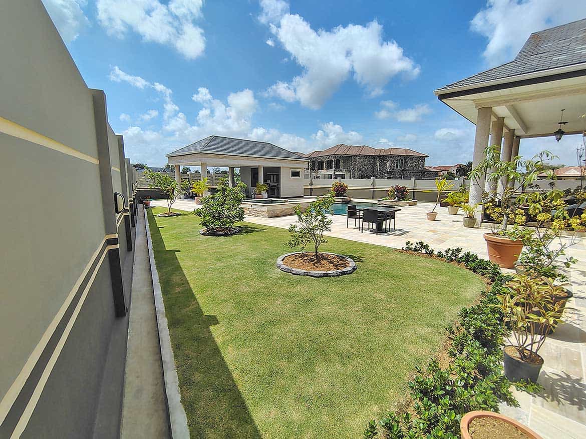 Millennium Lakes Home Garden Cornerstone- Beautiful landscaped backyard with lawn, trees, and outdoor seating area.