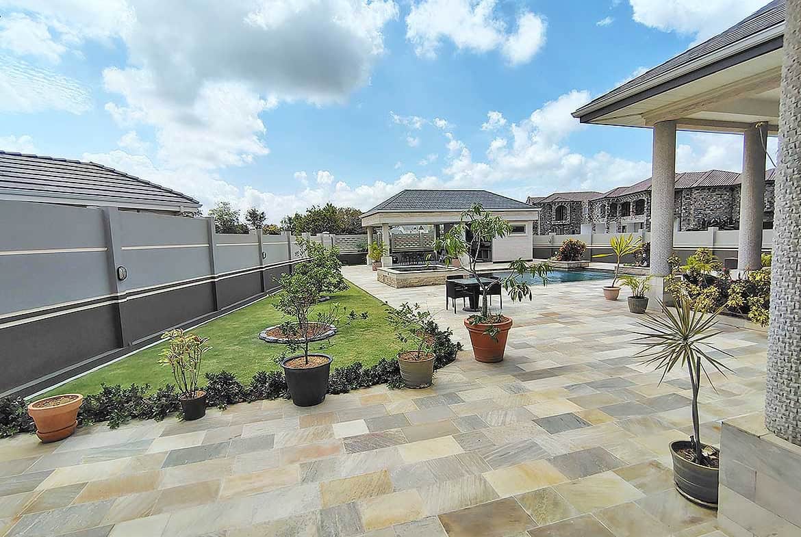 Cornerstone- Spacious outdoor patio with potted plants and garden area at Millennium Lakes Home.