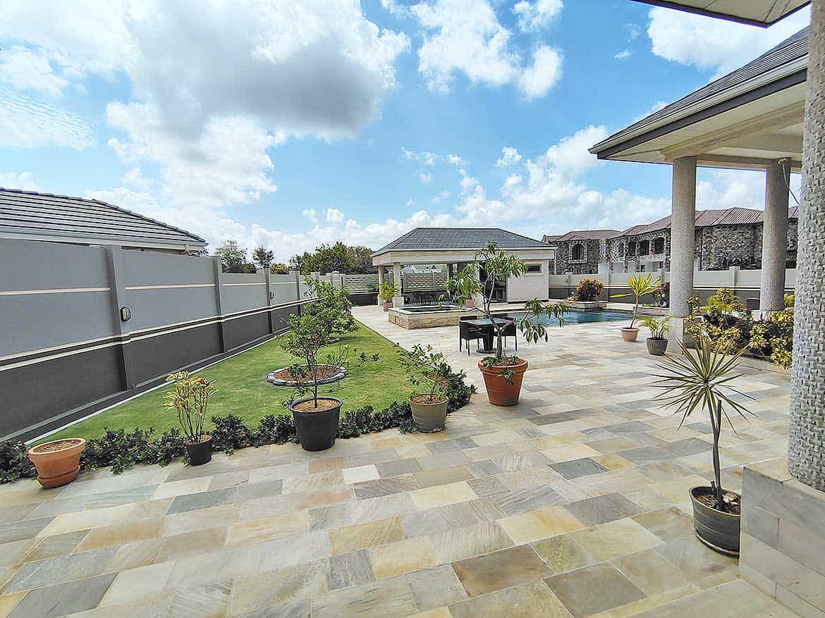 Millennium Lakes Home Outdoor Patio Cornerstone- Spacious outdoor patio with potted plants and garden area at Millennium Lakes Home.