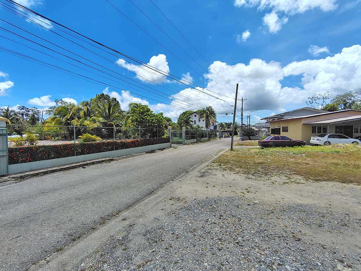 Off Ajim Baksh Road Scene Cornerstone- View of Ajim Baksh Road with houses and power lines under blue sky.