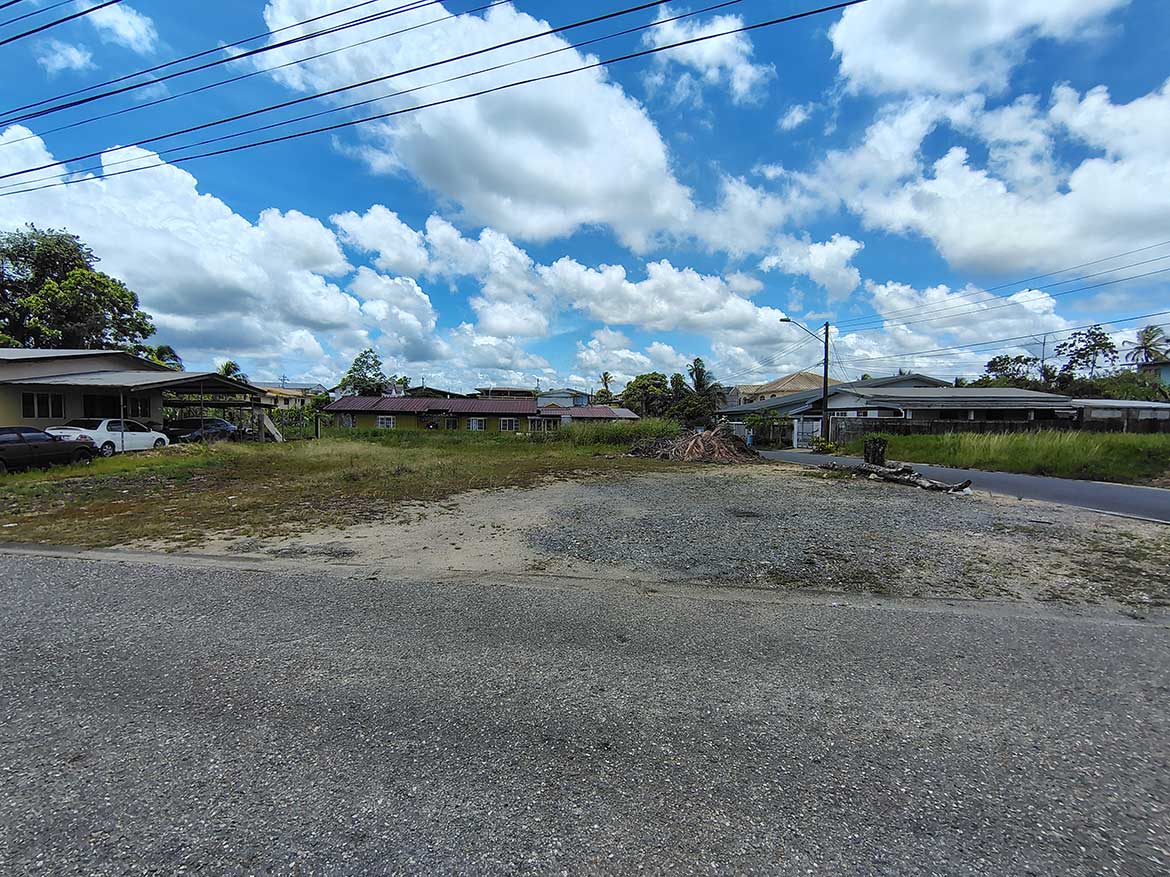 Off Ajim Baksh Road – Cornerstone™ Cornerstone- Open lot on Ajim Baksh Road with houses and power lines under a blue sky.