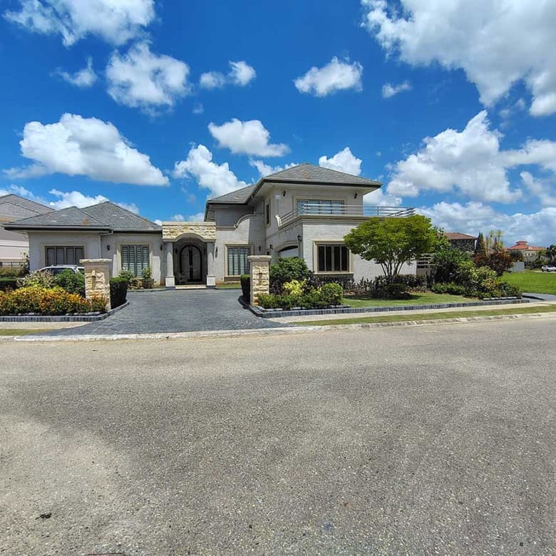 Cornerstone- Elegant modern house with landscaped garden and blue sky.