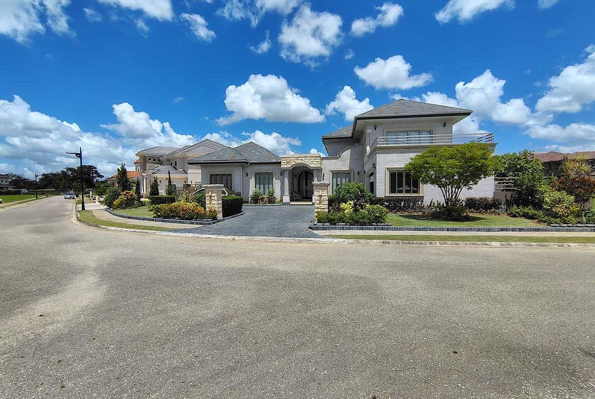 Cornerstone- Elegant modern house with landscaped garden and blue sky backdrop.