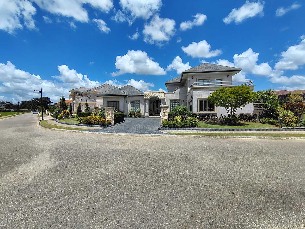 Luxury Home at Millennium Lakes Cornerstone- Elegant modern house with landscaped garden and blue sky backdrop.