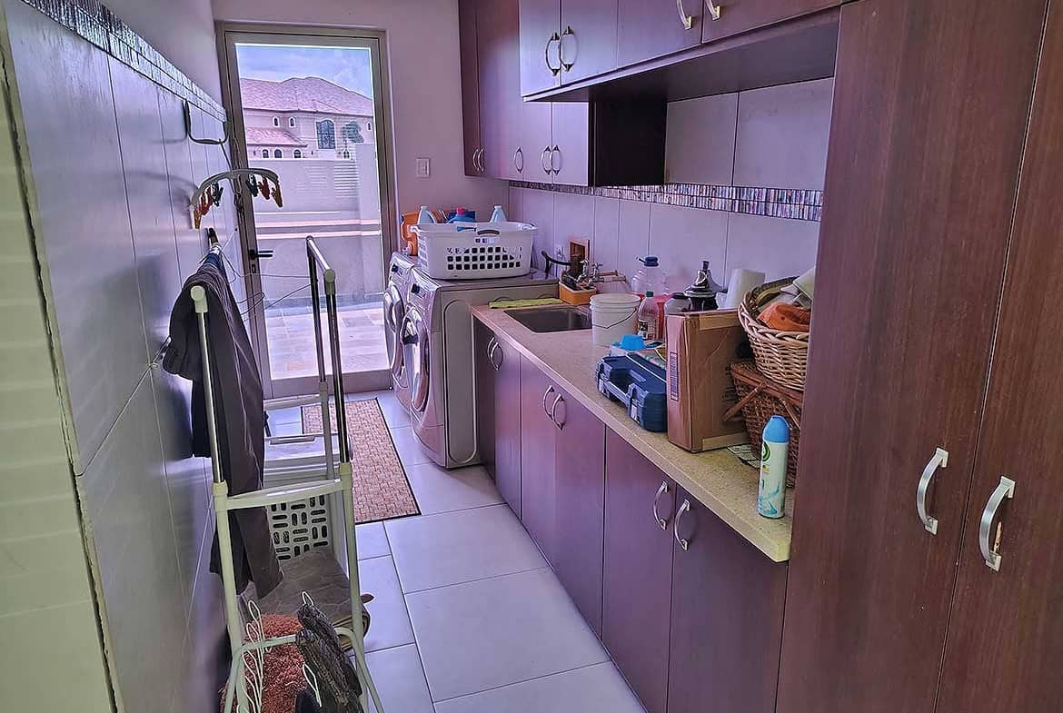 Cornerstone- Laundry room with washing machine, cabinets, and cleaning supplies.
