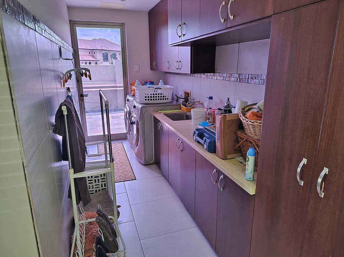Cornerstone™ Laundry Room Cornerstone- Laundry room with washing machine, cabinets, and cleaning supplies.