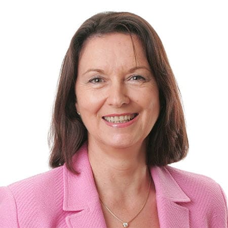 Cornerstone- Businesswoman smiling in pink blazer for real estate investment.