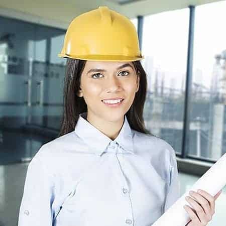 Cornerstone- Female engineer wearing yellow hard hat holding blueprints in modern office.
