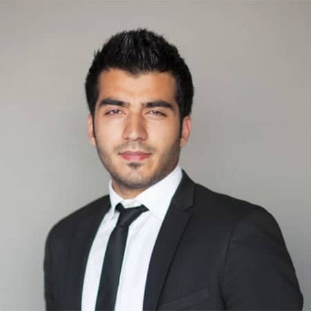Cornerstone- Confident real estate agent in formal suit with neutral background.