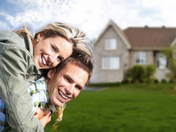 Cornerstone- Joyful couple celebrating in front of their new home.