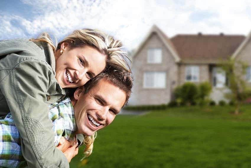 Cornerstone- Joyful couple celebrating in front of their new home.