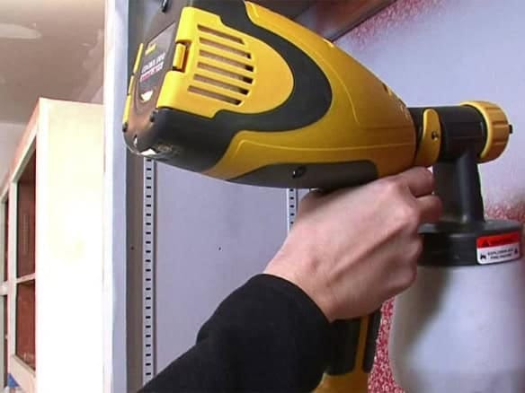 Cornerstone- Person using a yellow cordless drill on a wall for home improvement.