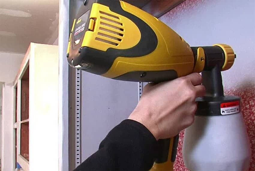 Cornerstone- Person using a yellow cordless drill on a wall for home improvement.