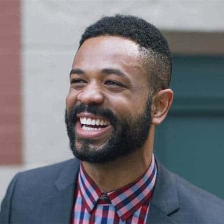 Cornerstone- Smiling man in business attire with a beard and short hair.