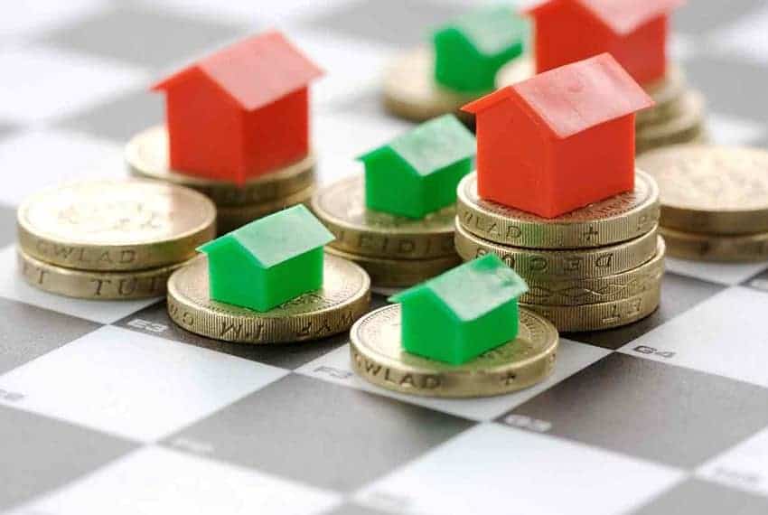 Cornerstone- Miniature houses on coins representing property valuation and real estate investment.