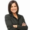 Cornerstone- Confident businesswoman smiling with arms crossed, professional appearance.