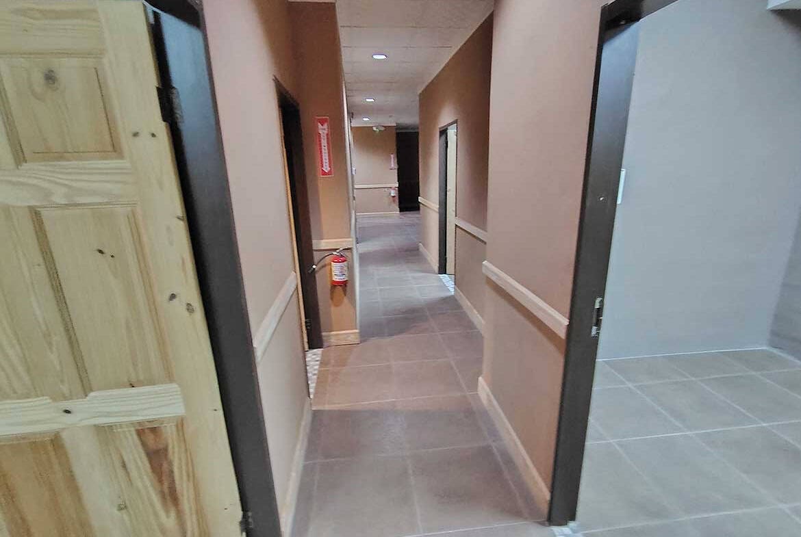 Cornerstone- Indoor corridor of e TecK Building with beige walls and tiled flooring.