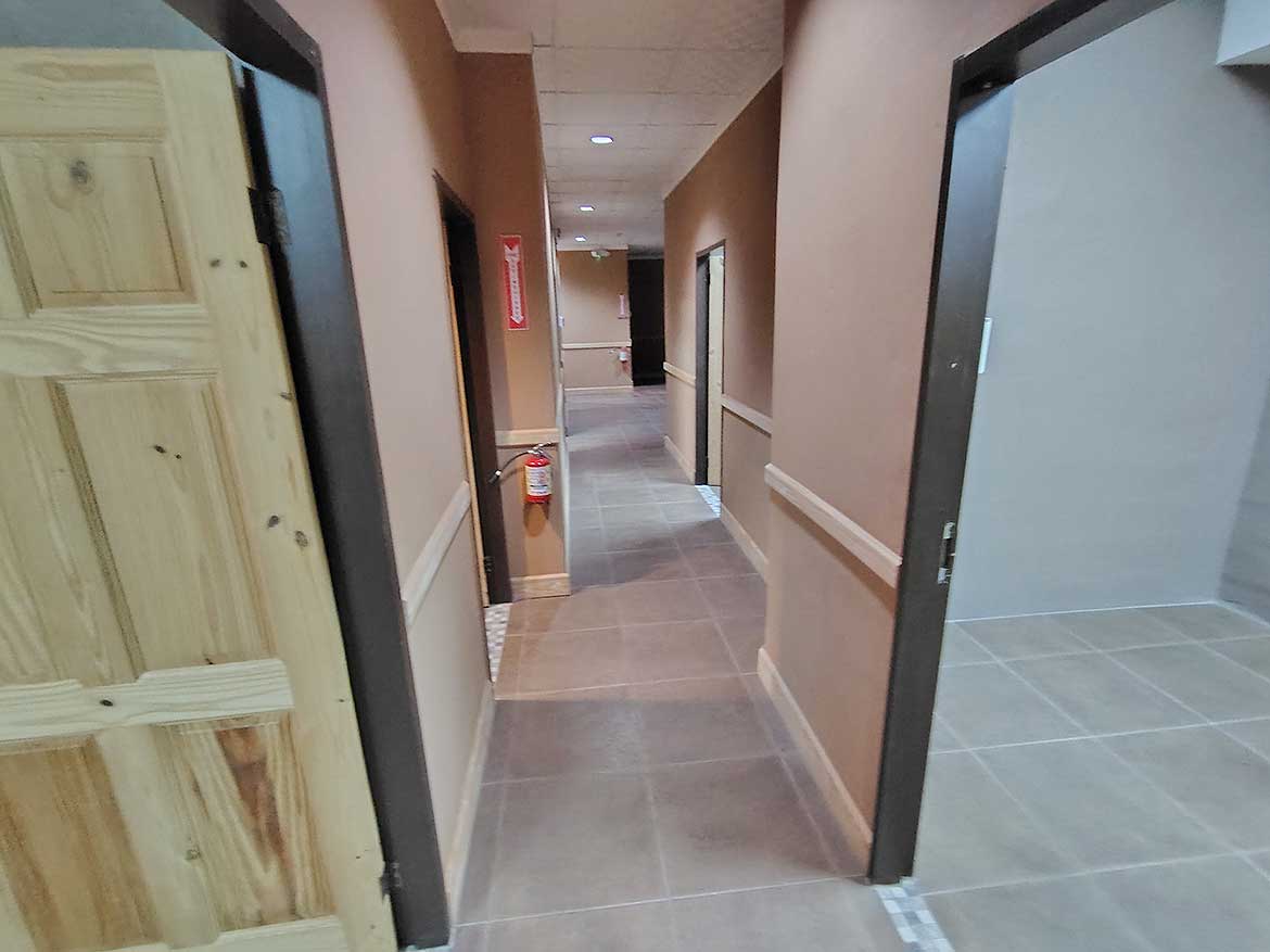 Interior Hallway of e TecK Building Cornerstone- Indoor corridor of e TecK Building with beige walls and tiled flooring.