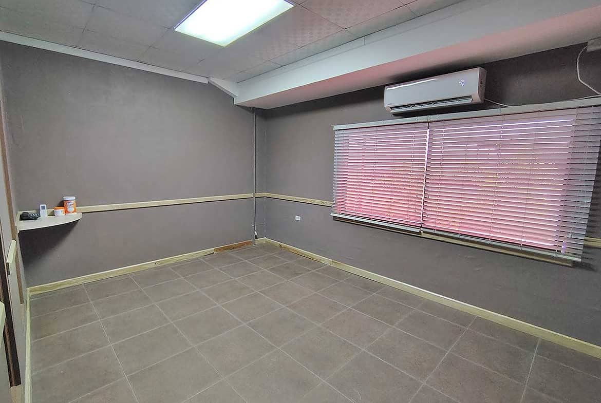 Cornerstone- Empty office room with gray walls, window blinds, and air conditioning unit.