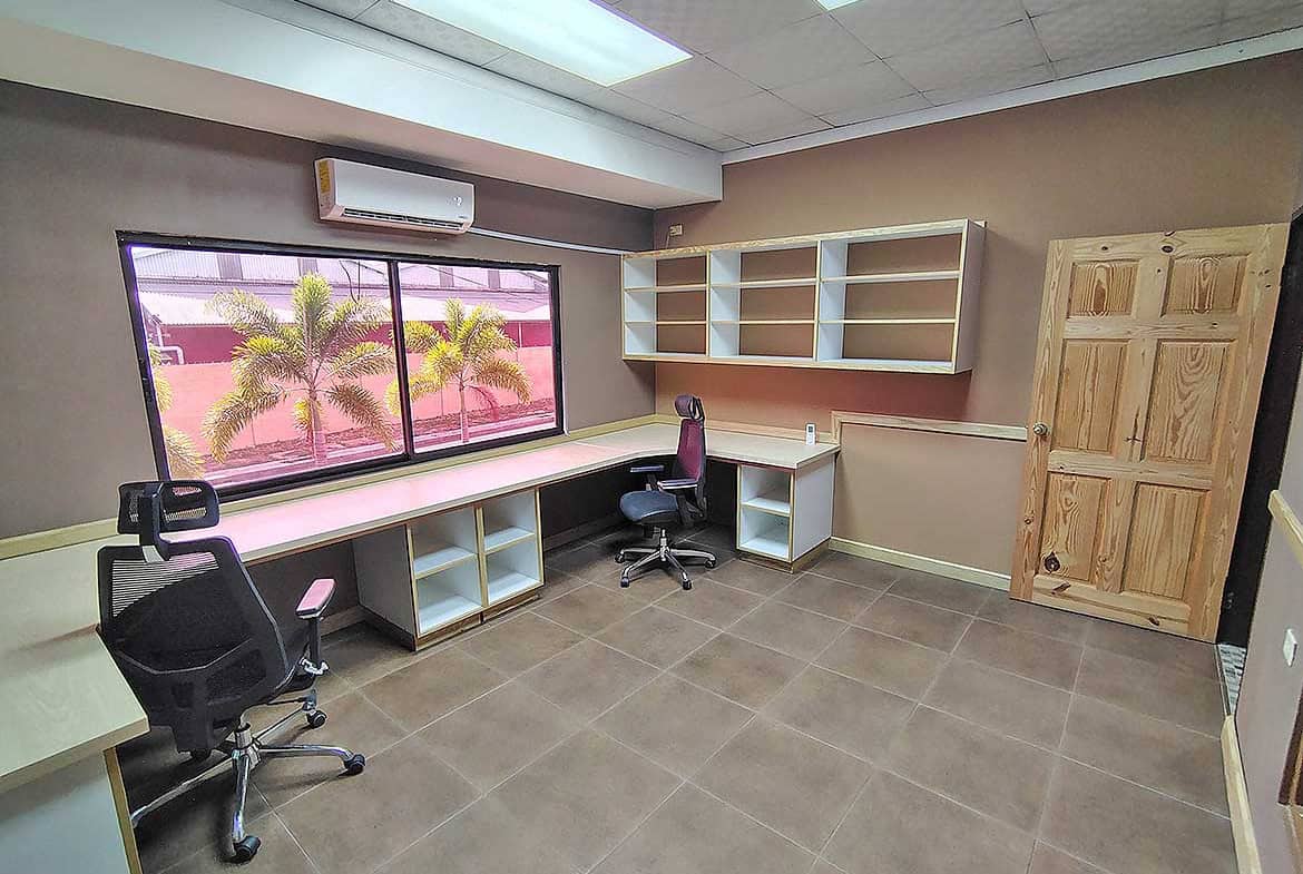 Cornerstone- Modern office workspace with desks, chairs, and shelves at e TecK Building.