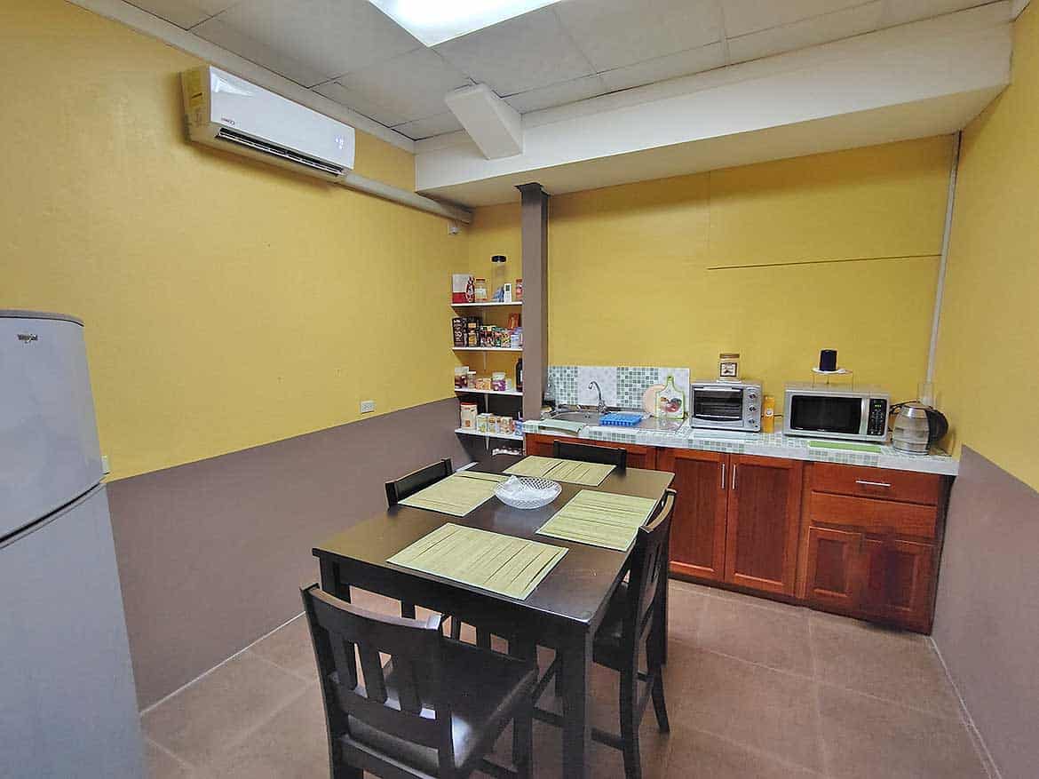 Cornerstone™ Office Kitchen Area Cornerstone- Office kitchen with yellow walls, wooden cabinets, microwave, and dining table.