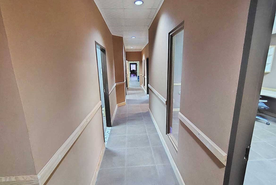 Cornerstone- Long corridor inside e TecK Building with beige walls and windows.