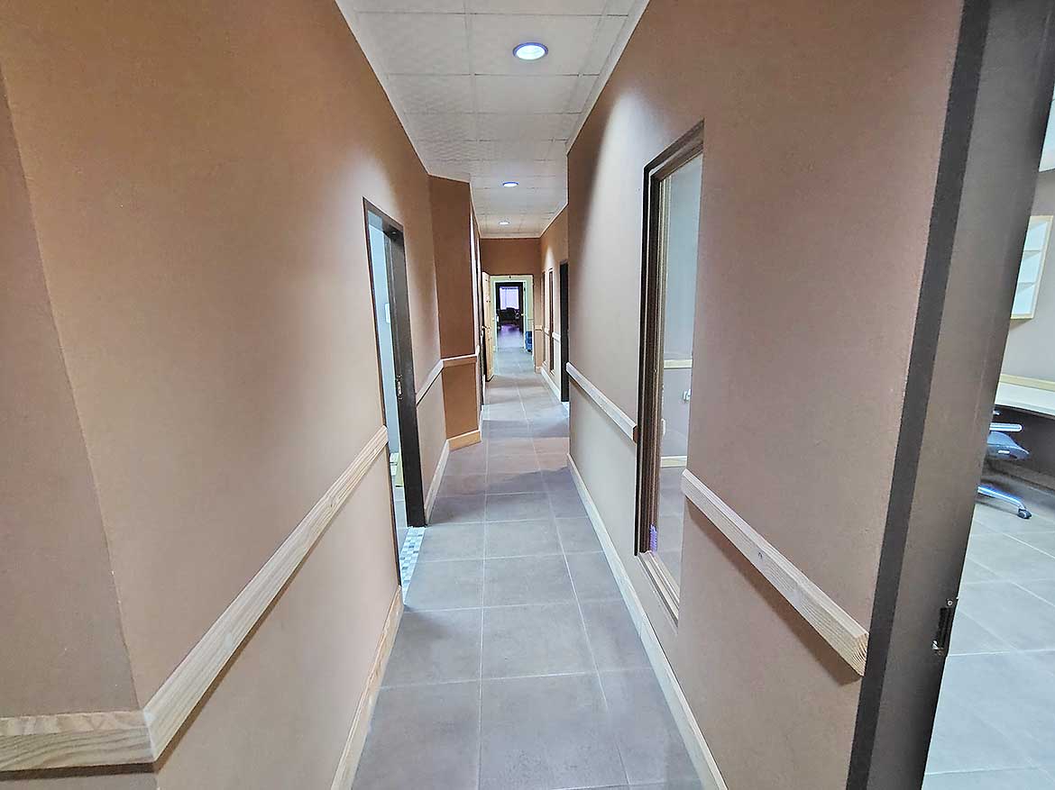 Interior Hallway at e TecK Building Cornerstone- Long corridor inside e TecK Building with beige walls and windows.