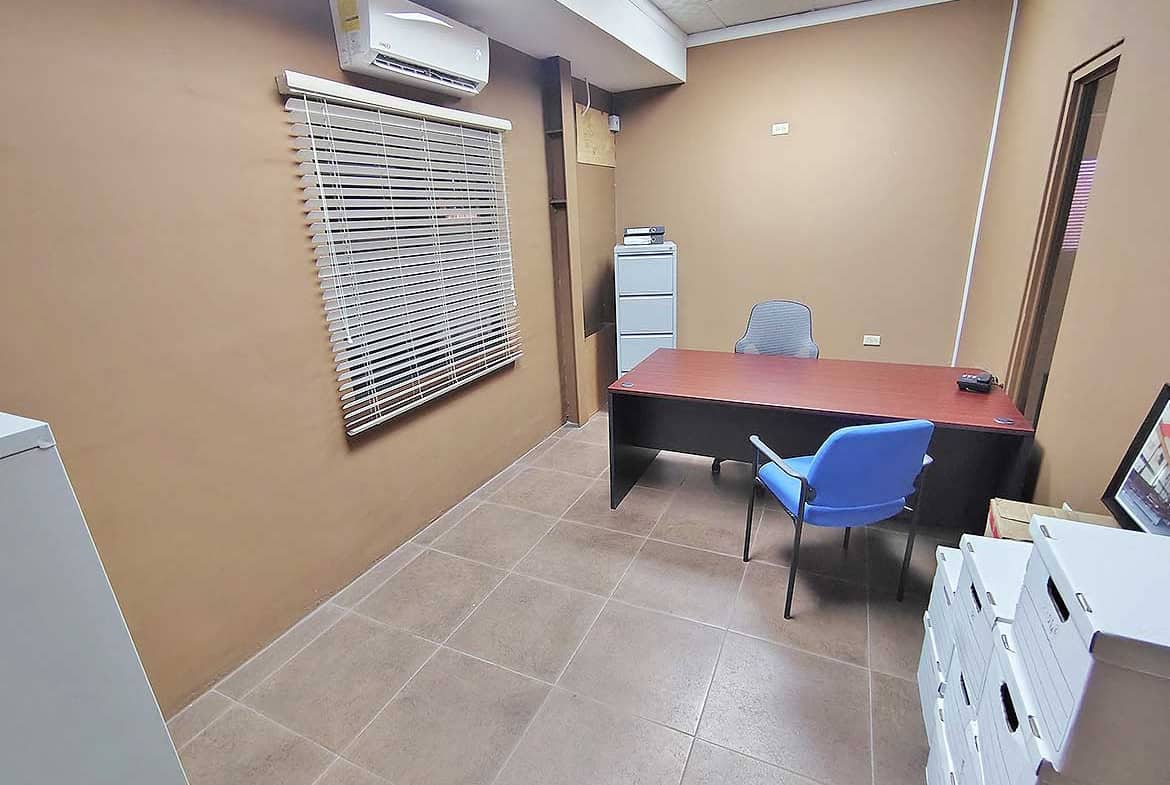 Cornerstone- Interior of an office with desk, chairs, and air conditioning unit.