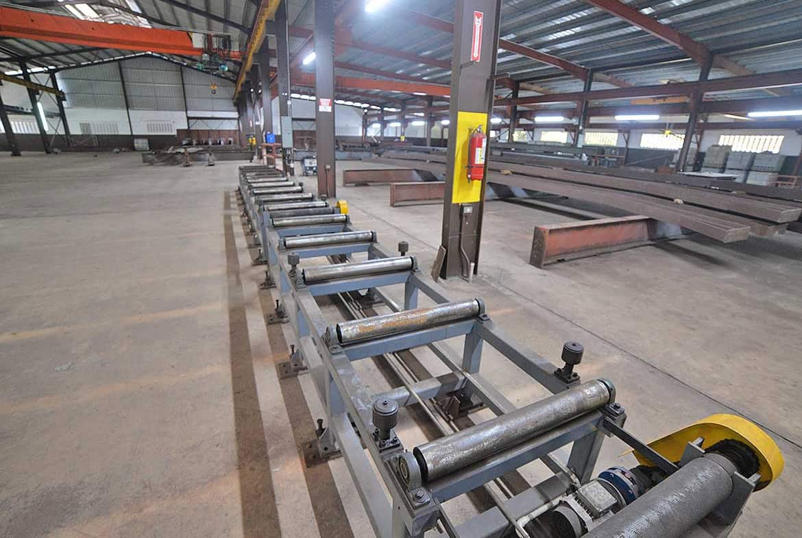 Cornerstone- Steel beam processing machinery in a large industrial warehouse.