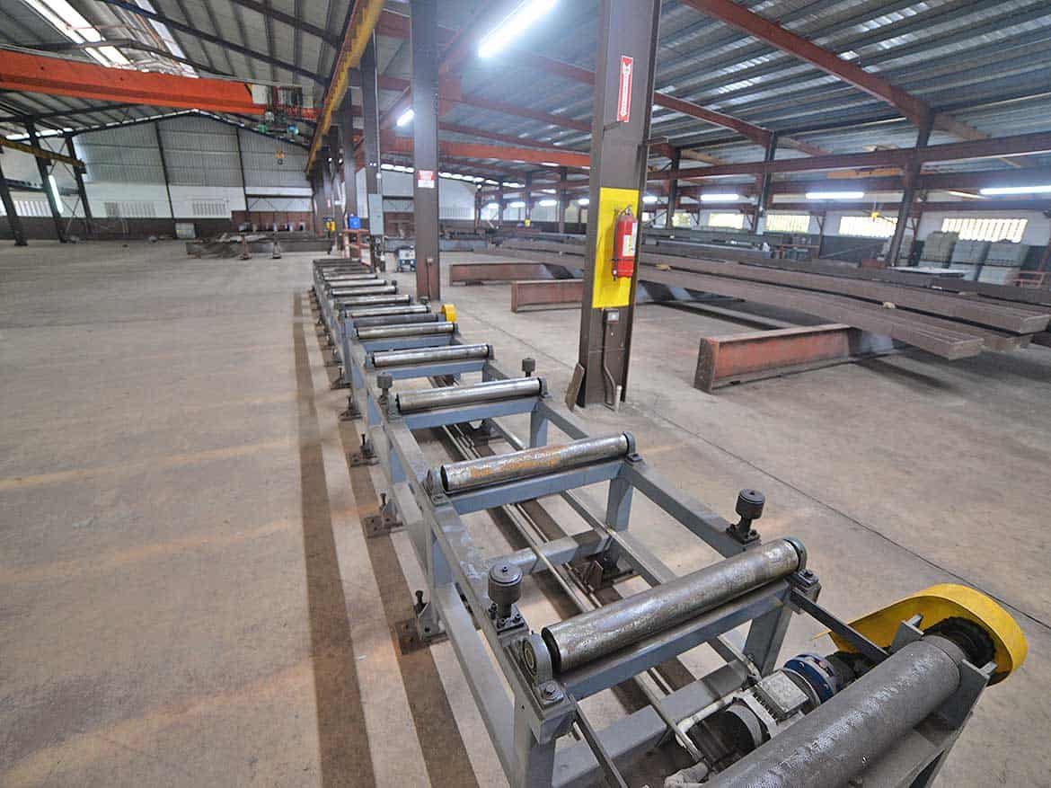 Industrial Steel Beam Processing Equipment Cornerstone- Steel beam processing machinery in a large industrial warehouse.