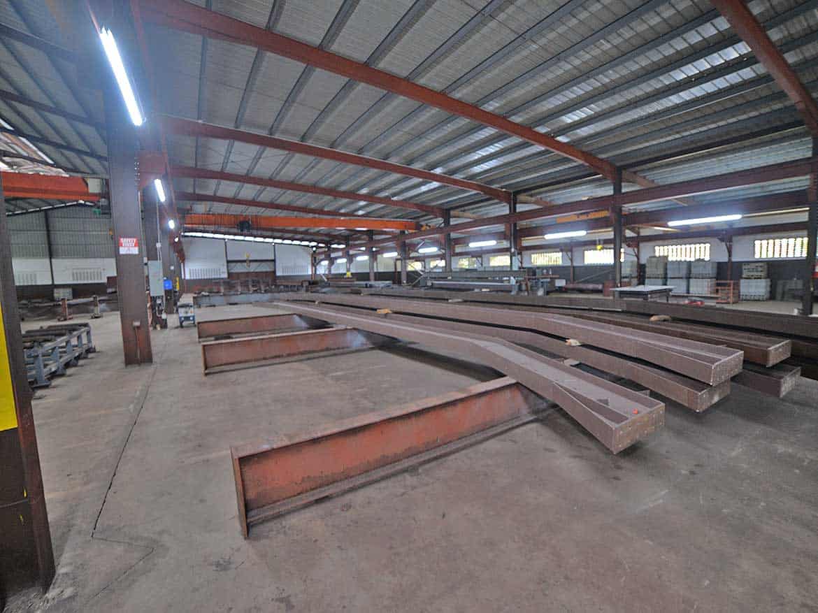 Industrial Steel Beams at Cornerstone Cornerstone- Large steel beams stored in a spacious industrial warehouse for construction.