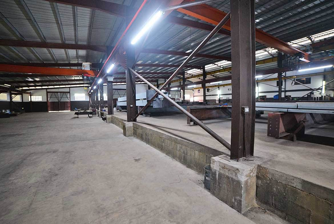 Cornerstone- Interior of an industrial warehouse under construction with steel beams and lighting.