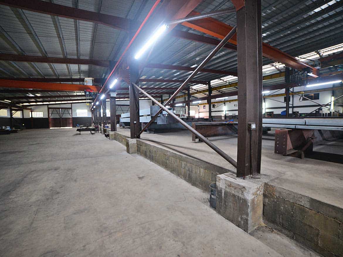 Industrial Warehouse Construction Site Cornerstone- Interior of an industrial warehouse under construction with steel beams and lighting.