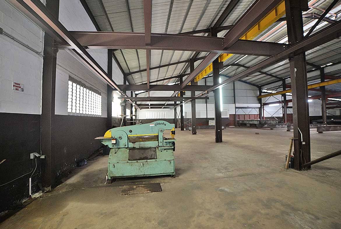 Cornerstone- Spacious industrial warehouse interior with machinery and steel framework.