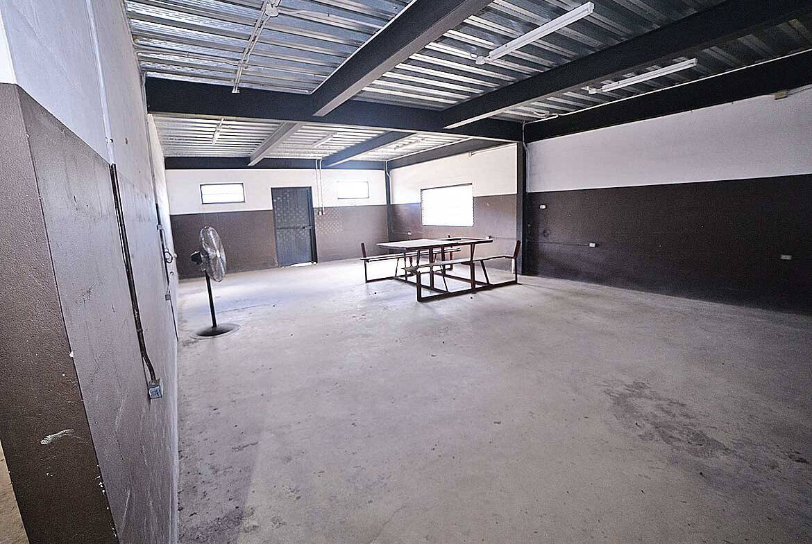 Cornerstone- Spacious industrial warehouse interior with concrete floor and metal roof.