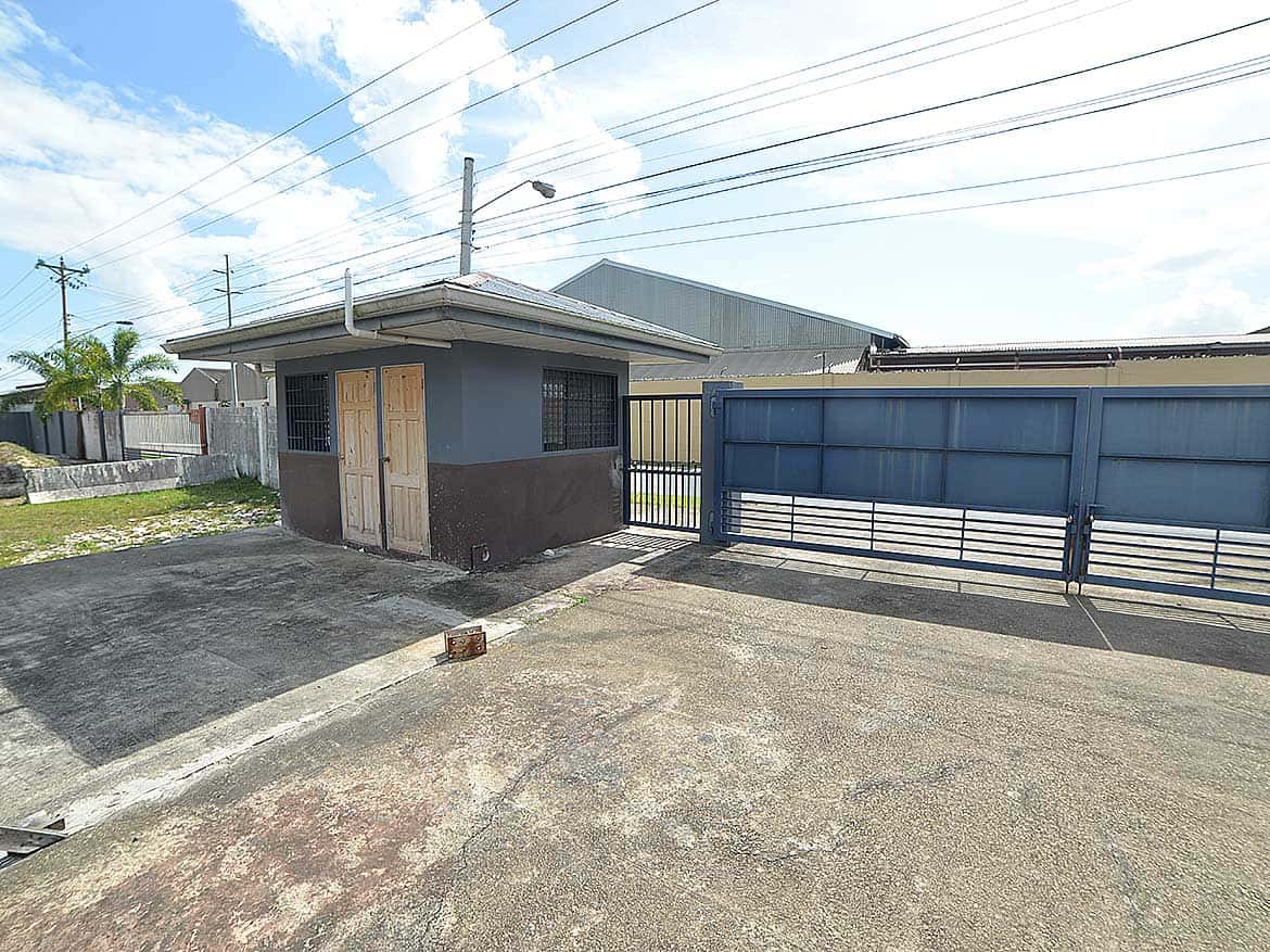 O’Meara e TecK Building Entrance Cornerstone- Small building with blue gate at O'Meara e TecK site in Trinidad.
