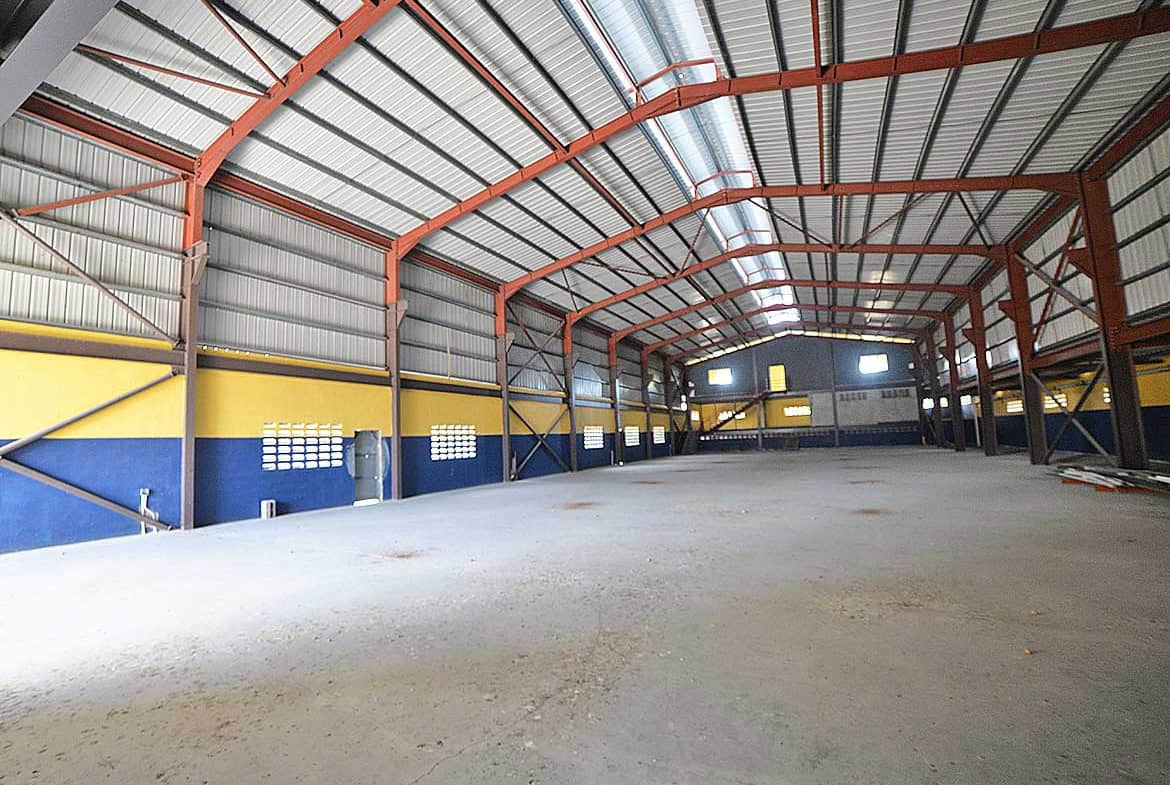 Cornerstone- Spacious industrial warehouse interior with high ceilings and metal framework.