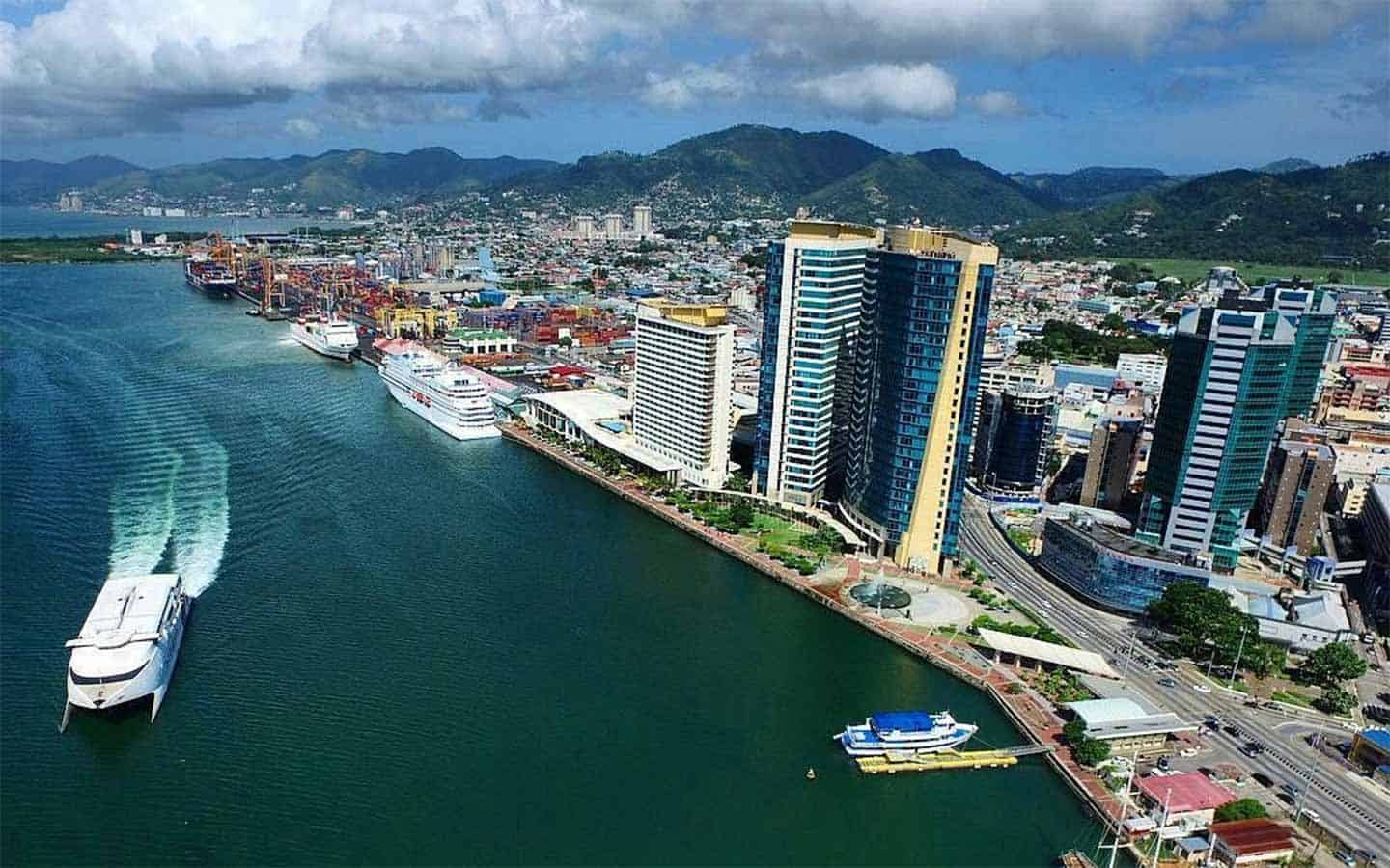 Cornerstone- Aerial view of Port of Spain with high-rise buildings and ships in the harbor.
